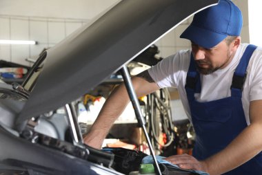 Profesyonel oto tamircisi servis merkezinde modern arabayı tamir ediyor.