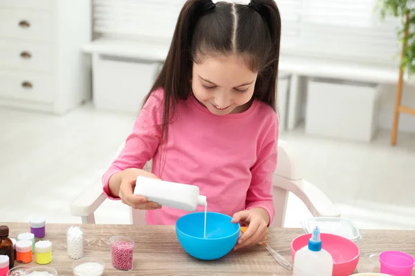 Cute Little Girl Pouring Glue Into Bowl At Table In Room Diy Slime Toy Fun Fluffy Stock Photo