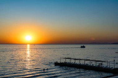 Güzel, renkli ve zıt bir gün batımı denizin üzerinde, okyanusun üzerinde. Sıcak güneş geniş araziyi aydınlatarak su yüzeyine ışıldayan ışınlar saçar. Parlak Sunny gün doğumu. Seyahat ve turizm