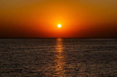 Güzel, renkli ve zıt bir gün batımı denizin üzerinde, okyanusun üzerinde. Sıcak güneş geniş araziyi aydınlatarak su yüzeyine ışıldayan ışınlar saçar. Parlak Sunny gün doğumu. Seyahat ve turizm