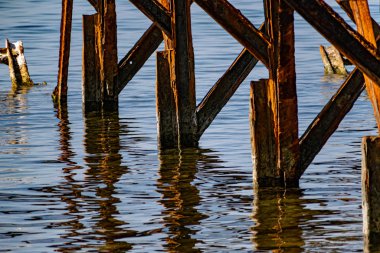 Çok paslı metal çerçeveler, tuzlu deniz suyundan aşınmaya maruz kalan eski kalın metaller. Güneş ışığında kırmızı parlak bir renk