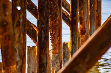 Çok paslı metal çerçeveler, tuzlu deniz suyundan aşınmaya maruz kalan eski kalın metaller. Güneş ışığında kırmızı parlak bir renk