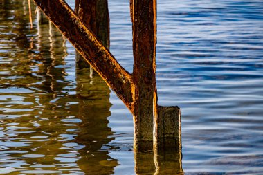 Çok paslı metal çerçeveler, tuzlu deniz suyundan aşınmaya maruz kalan eski kalın metaller. Güneş ışığında kırmızı parlak bir renk