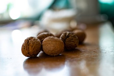 Katı ve kabartmalı kahverengi kabuklu cevizler, sert güneş ışığıyla aydınlatılmış, ahşap bir masanın üzerinde yatıyor.