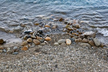 Tuzlu deniz suyunun kıyı dalgalarında büyük ve pürüzsüz taşlar. Karadeniz kıyıları, güneş ışığıyla aydınlatılan büyük bir çakıl taşına karşı kükreyen köpükler ve kükremeler.