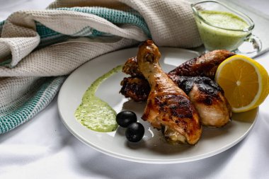 Kızarmış tavuk budu, kahverengi altın hamurlu ve taze soslu limon ve siyah zeytinlerle süslenmiş beyaz desenli peçeteyle, havluyla