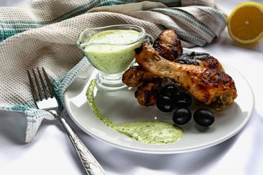 Kızarmış tavuk budu, kahverengi altın hamurlu ve taze soslu limon ve siyah zeytinlerle süslenmiş beyaz desenli peçeteyle, havluyla