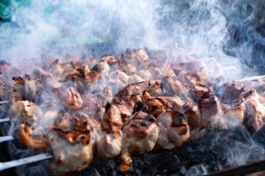 Ağız sulandıran domuz şişleri, kızarmış altın hamurlu ve dumanlı. Bahçede kömürlü barbekü ve şişte pişmiş et.