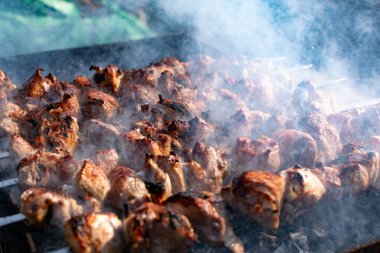 Ağız sulandıran domuz şişleri, kızarmış altın hamurlu ve dumanlı. Bahçede kömürlü barbekü ve şişte pişmiş et.