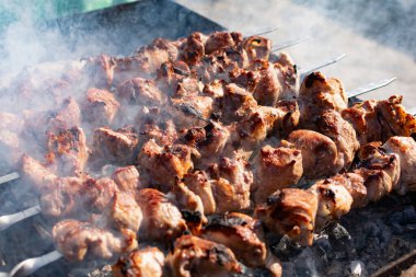 Ağız sulandıran domuz şişleri, kızarmış altın hamurlu ve dumanlı. Bahçede kömürlü barbekü ve şişte pişmiş et.