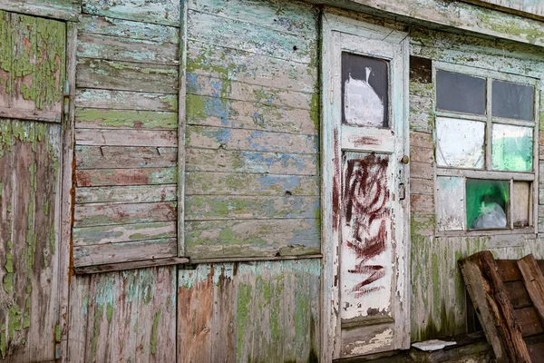 Old wooden doors on a collapsing building, a vintage barn, peeling paint, littered planks, the construction site is tilted to one side and damaged by temporary dirt