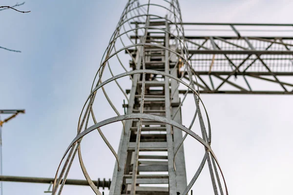 A metal structure made of thin but strong rings , chained together in a high tower stand for elevation to the top, covered with gray paint