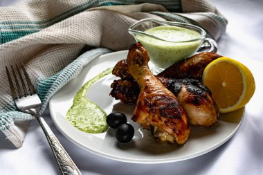 Kızarmış tavuk budu, kahverengi altın hamurlu ve taze soslu limon ve siyah zeytinlerle süslenmiş beyaz desenli peçeteyle, havluyla