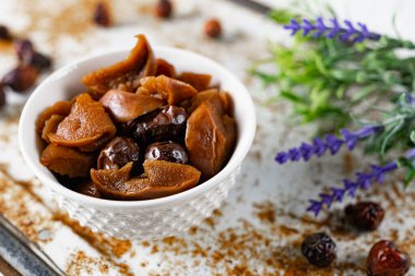 Tatlı ve yumuşak kurutulmuş elma ve tatlı için hazırlanmış gül kalçaları, alışılmadık beyaz ve paslı metal arka planda lavanta ve kuru meyvelerle süslenmiş.