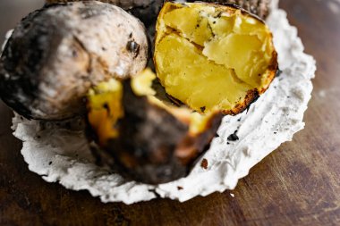 Köyün tarifine ve metoduna göre, doğrudan küllerin içinde, derideki ateş patateslerinde pişmiş. Kömürleşmiş, kokulu yumru, beyaz taş tabakta sıcak bir tabak.