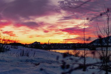 Açık bir günde gün batımında renkli gökyüzü çeşitli renklerle oynar, zıt ve zengin güzel dağ ve şehrin kışın parlaklığının görüntüsü.