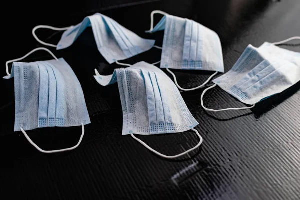 Disposable medical masks to protect against infections and viruses. White and blue layers with elastic bands for ears, on a black background