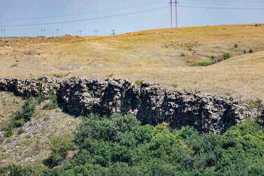Taşlı Zaitsev kayalarının Rostov bölgesinde alışılmadık bir manzara, yeşil yaprak döken ağaçlar, kuru sarı çimenler, mavi gökyüzü ve güneşli yaz ışığı.