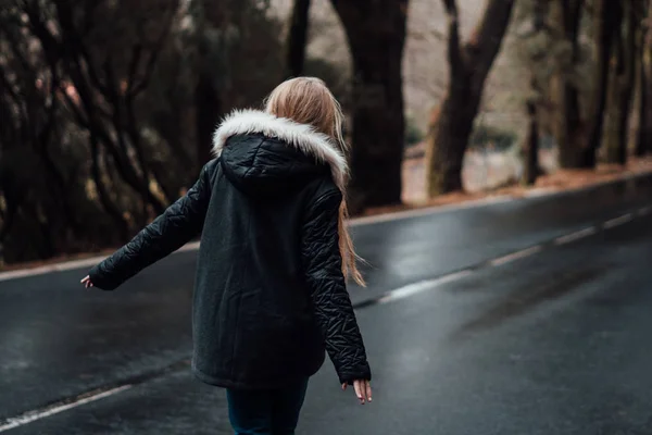 森の空道の上を歩く金髪の若い女性の後姿 — ストック写真