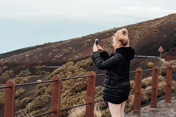 Sarışın kadının kırsal yol ve çekici fotoğraf smartphone ile ayakta arkadan görünüş