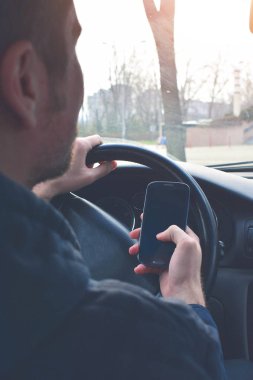 Yakışıklı adam araba sürüş sırasında Smartphone kullanarak