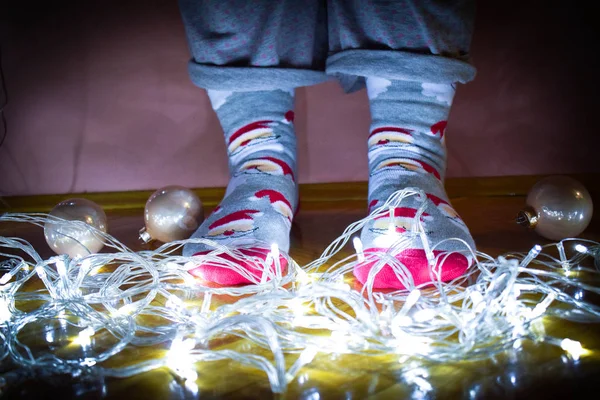 Girl\'s legs in seasonal winter socks with Christmas decoration. Funny Christmas socks. Cute Christmas socks with decoration in winter time