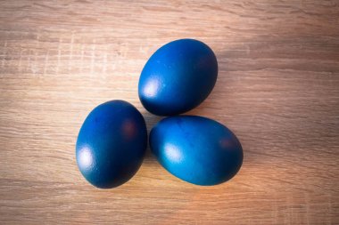 Ahşap zemin üzerinde üç mavi Paskalya yumurtaları