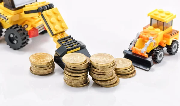 A toy bulldozer is collecting a pile of gold coins in a pile — Stock Photo, Image