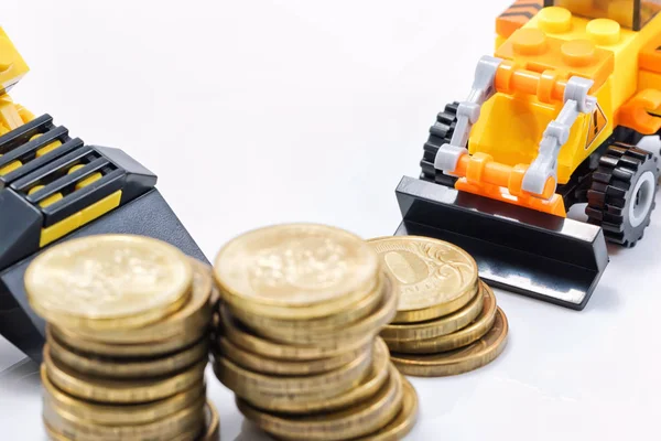A toy bulldozer is collecting a pile of gold coins in a pile — Stock Photo, Image