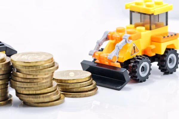 A toy bulldozer is collecting a pile of gold coins in a pile — Stock Photo, Image