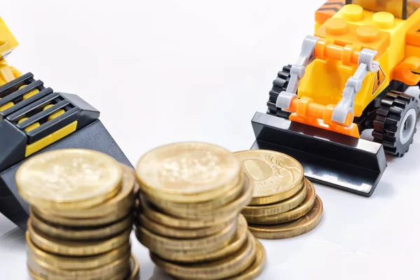 A toy bulldozer is collecting a pile of gold coins in a pile Royalty Free Stock Photos