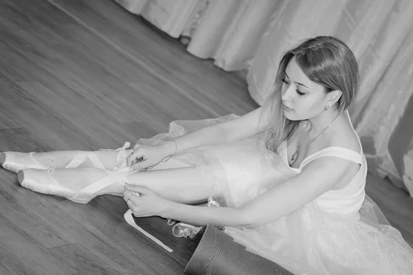 Charmoso jovem bailarina coloca em sapatos Pointe com fitas — Fotografia de Stock