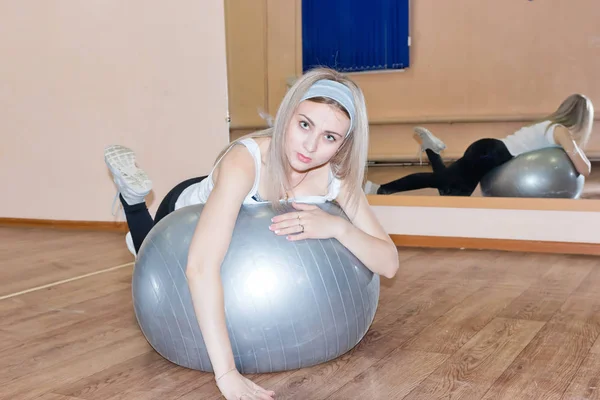 Chica joven agraciada hace ejercicios de fitness en una pelota de ejercicio — Foto de Stock