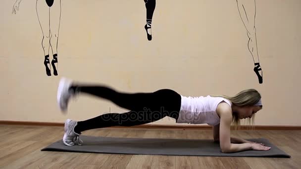 Красивая молодая девушка в спортивной одежде делает упражнения на растяжку лежа — стоковое видео