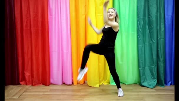 Красивая молодая девушка в спортивной одежде делает простые танцевальные движения — стоковое видео