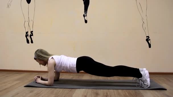 Beautiful young girl in sportswear does exercises on an extension lying — Stock Video