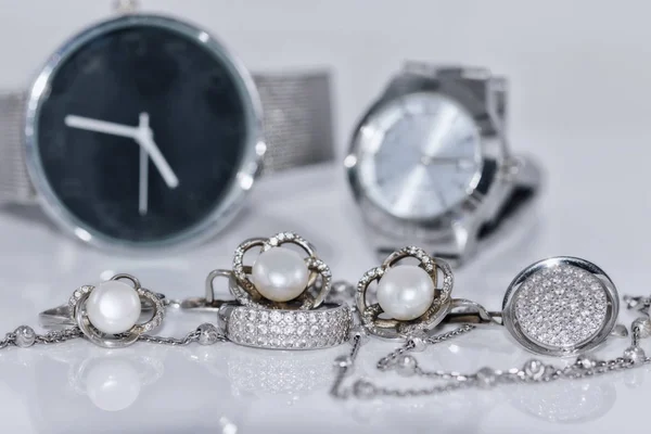 Silberohrringe mit Perle auf dem Hintergrund von Uhren — Stockfoto