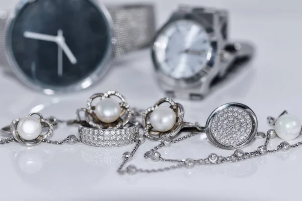 Boucles d'oreilles en argent avec perle sur le fond de montres — Photo