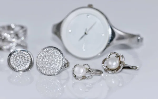 Stříbrné náušnice s perlou na pozadí hodinky — Stock fotografie