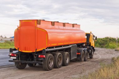 Kamyon üzerinde turuncu tanker ile yol kenarında park etmiş.