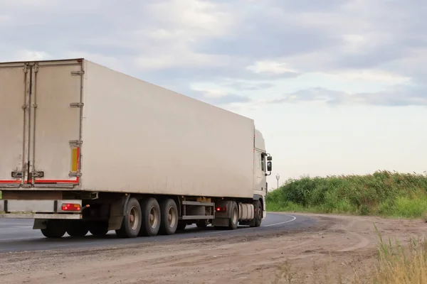 white lorry with white trailer over blue sky on the road