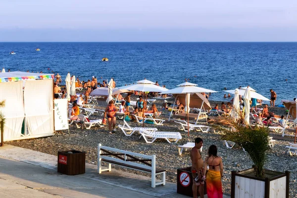 Turistas en la playa de la costa del mar negro, nadar y tomar el sol — Foto de Stock