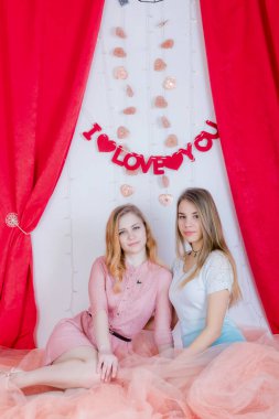 İki sevimli uzun saçlı kız elbiseler oturmak ve tekrar sarıl