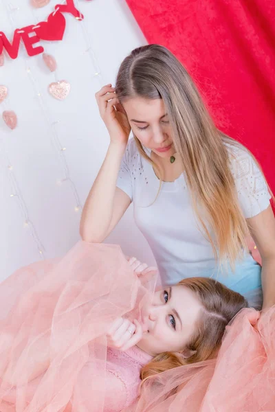 İki sevimli uzun saçlı kız elbiseler oturmak ve tekrar sarıl — Stok fotoğraf