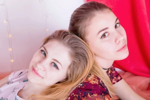 Portrait of two pretty girls sitting in a pose back to back — Stock Photo, Image