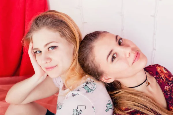 Portret dwóch ładne dziewczyny siedzi w pozie tyłem do — Zdjęcie stockowe