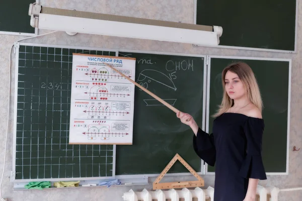 Young slender beautiful blonde teacher in a black dress — Stock Photo, Image