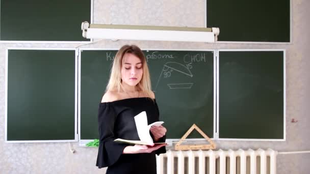 Αυστηρή Νεαρή Ξανθιά Δασκάλα Μαύρο Φόρεμα Σαρώνει Περιοδικό Και Ζητεί — Αρχείο Βίντεο