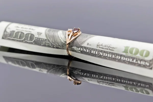 Hundred dollar bill is rolled into elegant women's gold ring — Stock Photo, Image