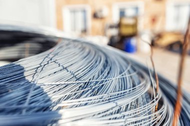 Büyük paslanmaz tel bobini ahşap paletin üzerinde duruyor.